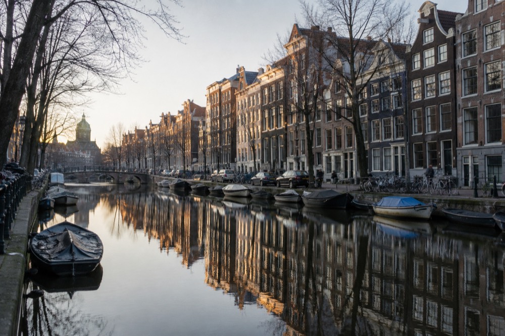 Row of narrow canal houses reflected in still canal water