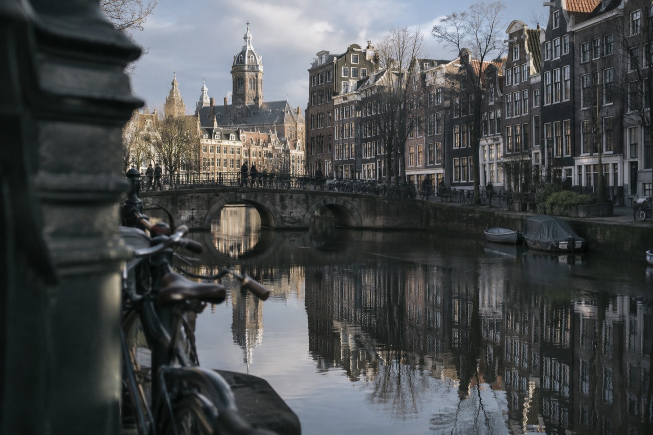 Amsterdam canal houses reflected in still water on a quiet morning