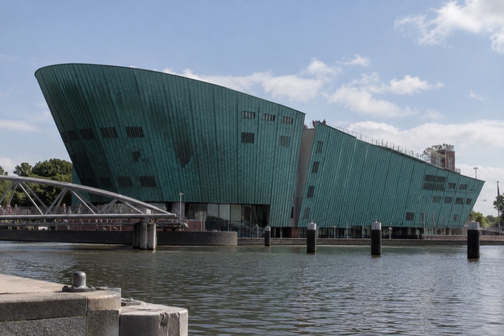 The green hull of the NEMO science museum building above the water with a terrace on its roof