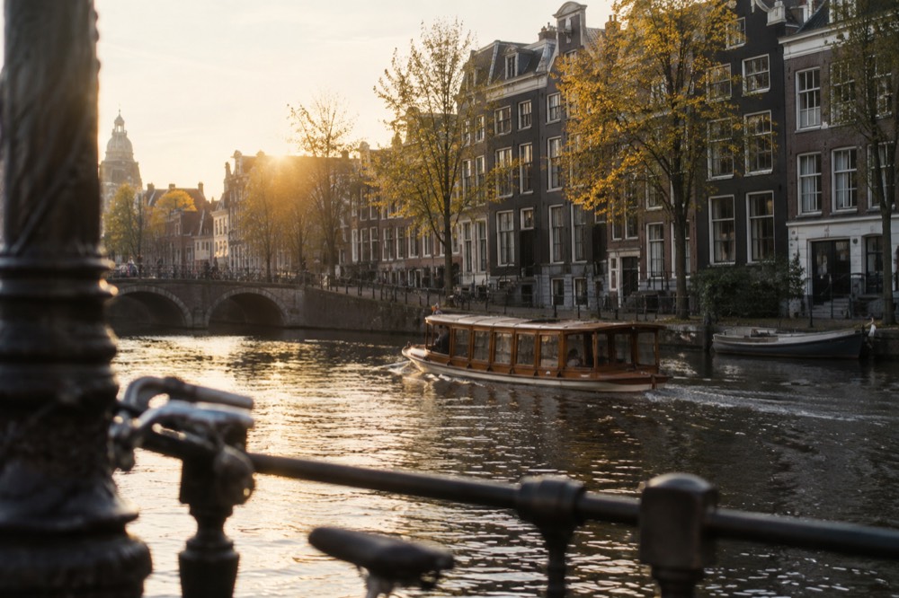 A traditional wooden saloon boat passing gabled canal houses