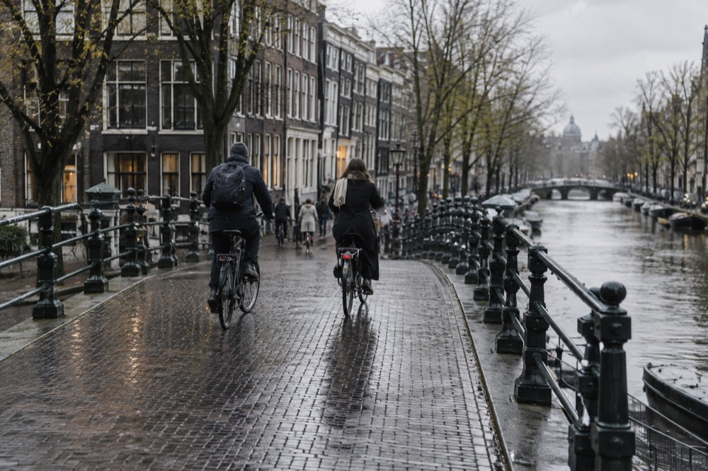 Cyclists crossing a small canal bridge in the Jordaan neighbourhood in the morning