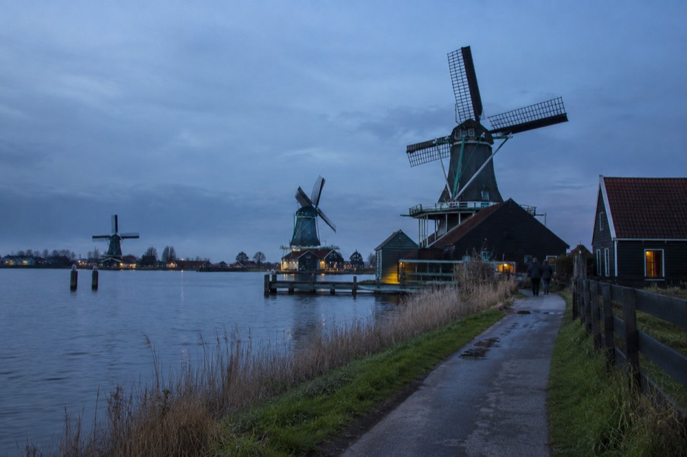Traditional Dutch windmills at Zaanse Schans standing along a riverbank under an open sky