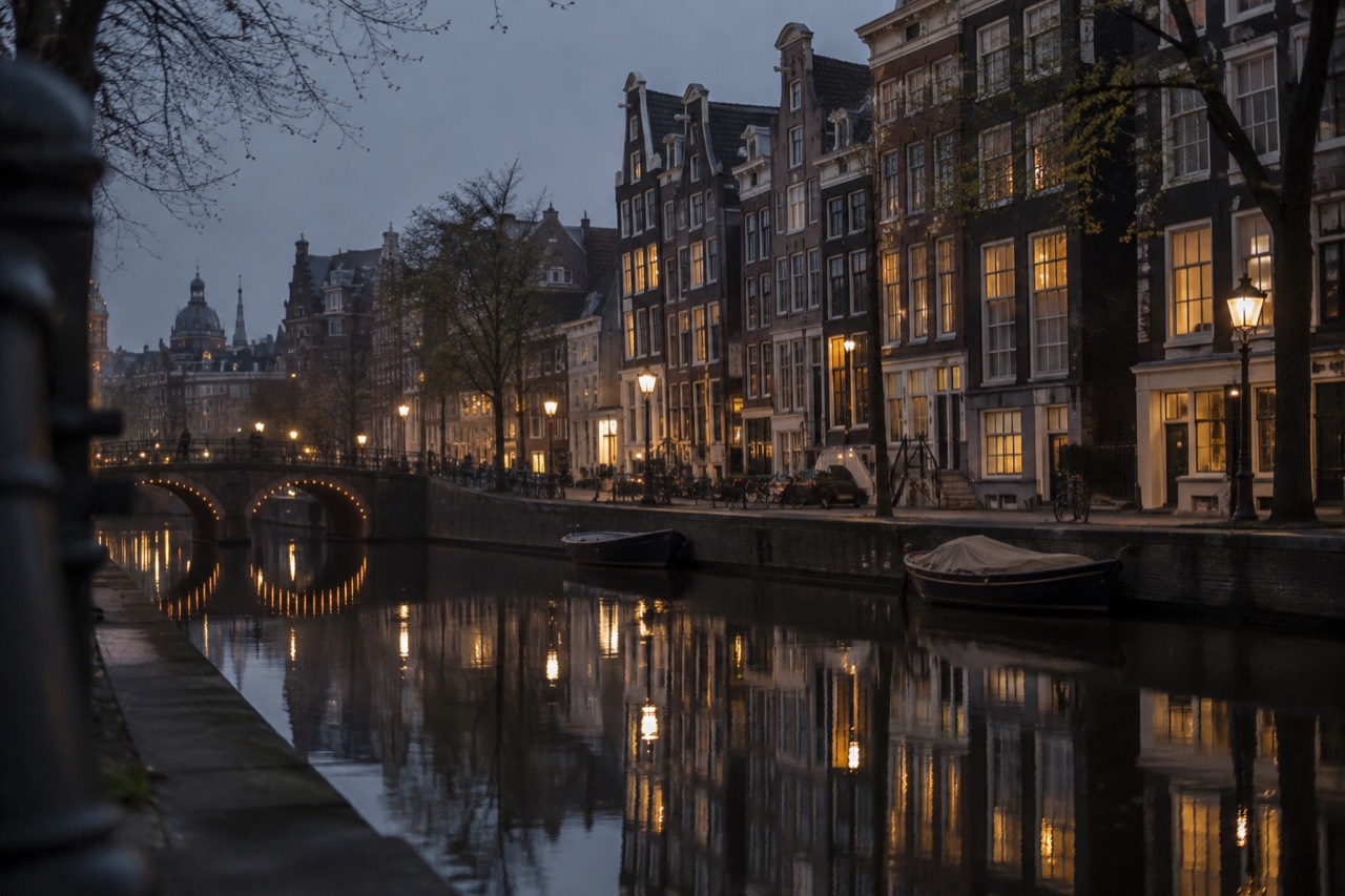 Amsterdam canal houses reflected in still water on a quiet morning