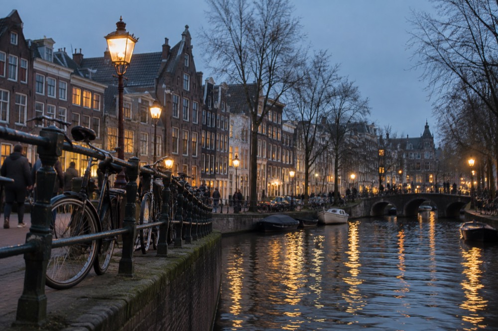 A canal in Amsterdam lined with narrow gabled houses and bicycles on a bridge