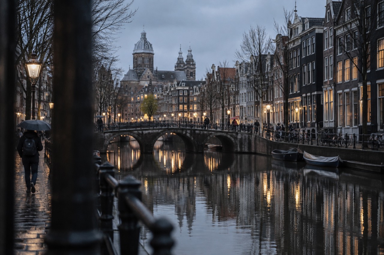 Amsterdam canal houses and bridge reflected in still water at dusk