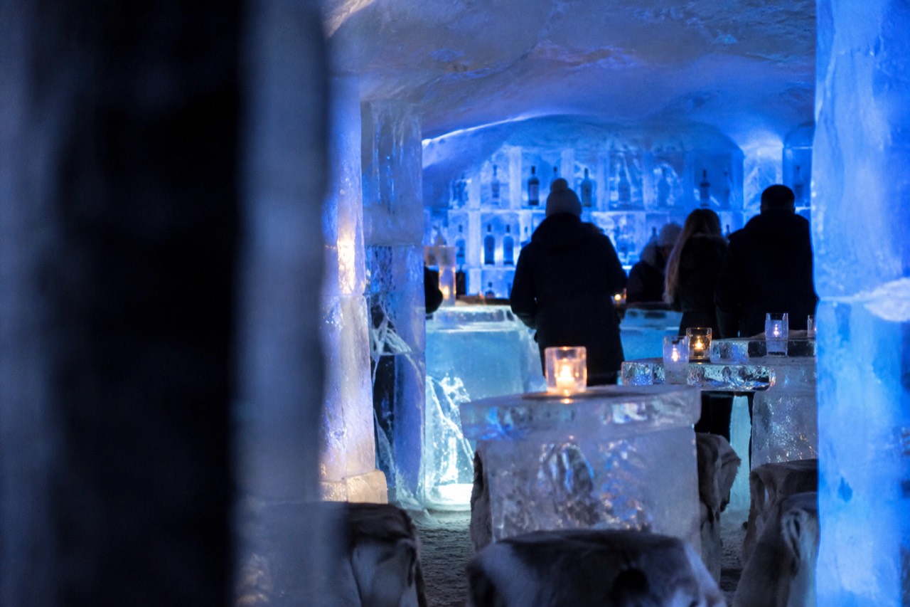 Frost-covered interior of an ice bar with glowing blue light on walls of carved ice