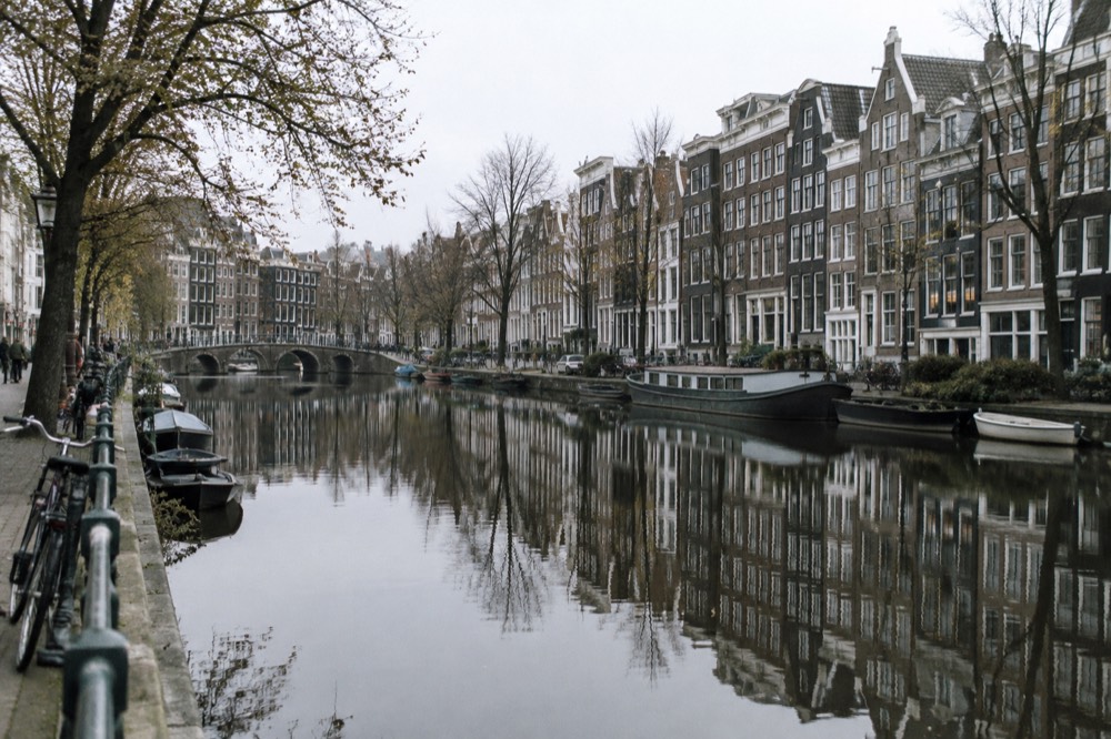 Amsterdam canal houses reflected in still water on a quiet morning