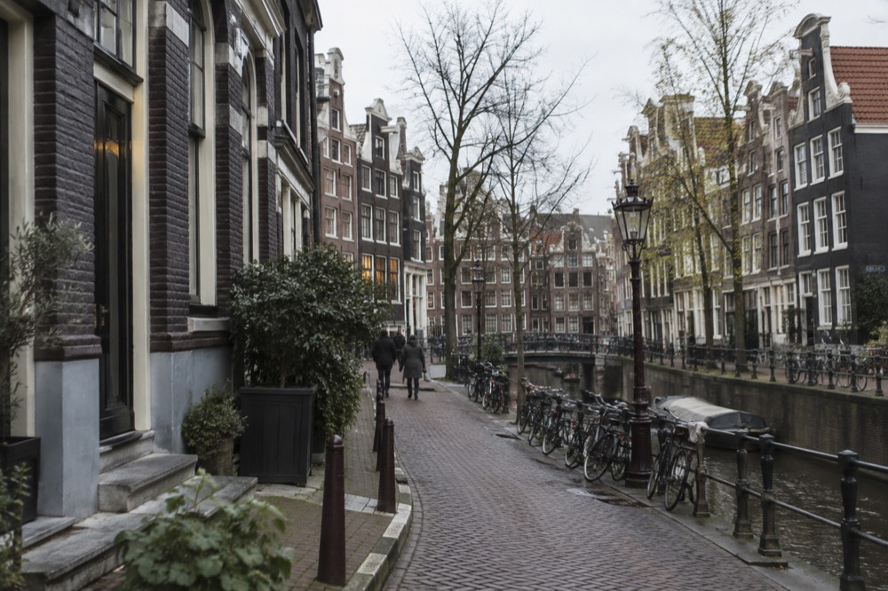 A narrow Amsterdam street with tall gabled houses and bicycles parked against the railings