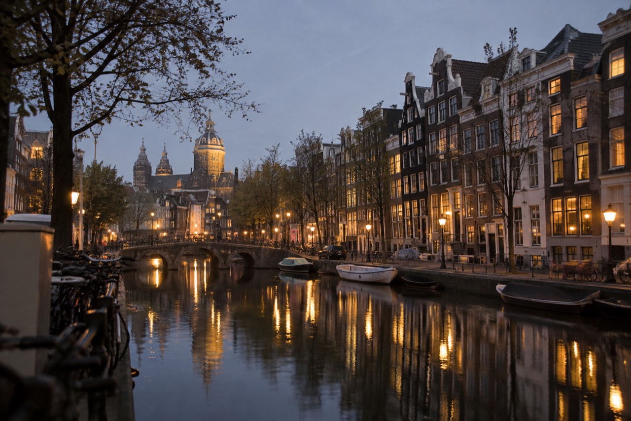 A canal in Amsterdam lined with narrow gabled houses reflected in still water