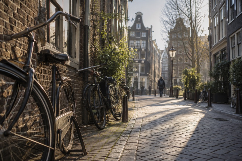 A narrow Amsterdam alley with tall gabled houses and bicycles leaning against a brick wall