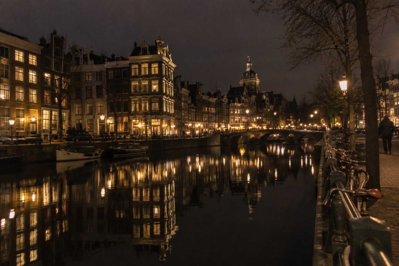 Illuminated canal houses reflected in still water at night