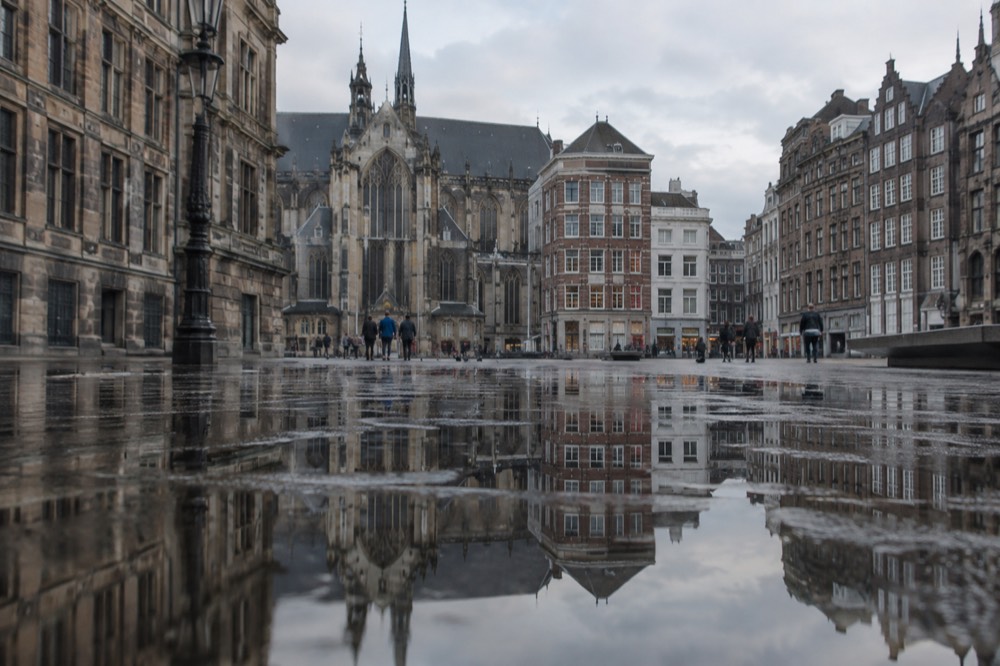 Amsterdam canal houses reflected in still water on a quiet morning