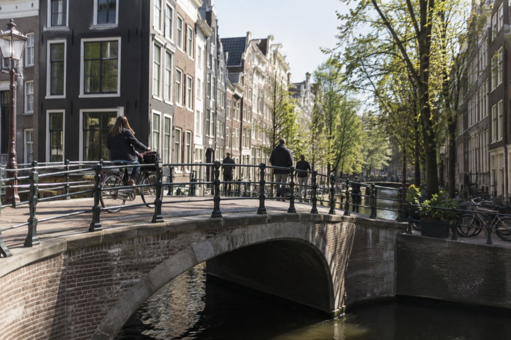 A bicycle crossing a small arched canal bridge in the Amsterdam city centre
