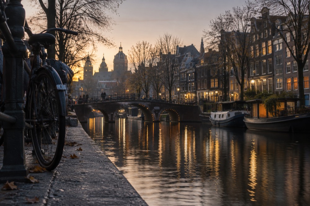 An Amsterdam canal at dusk with warm window lights reflecting on the water