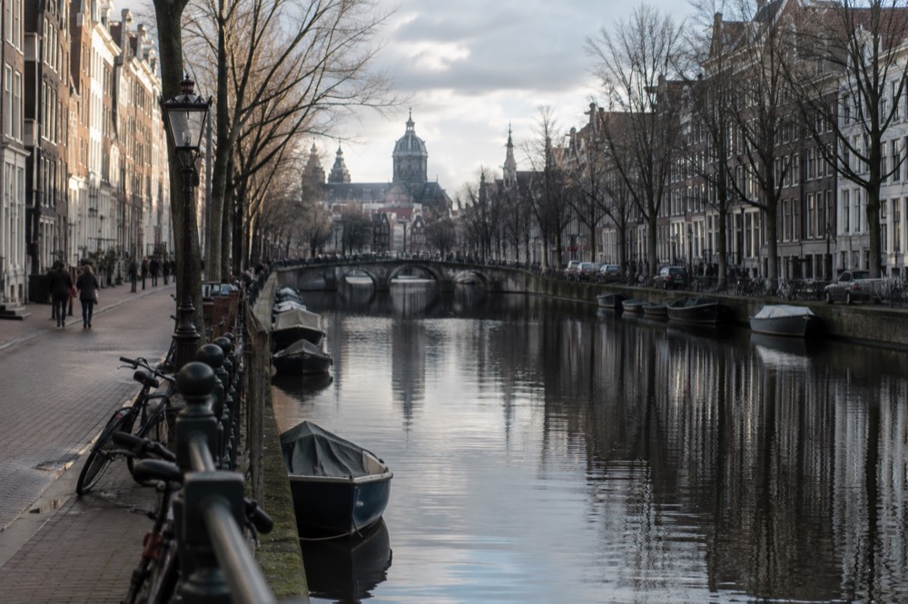A quiet Amsterdam canal in winter with bare trees and reflections in dark water
