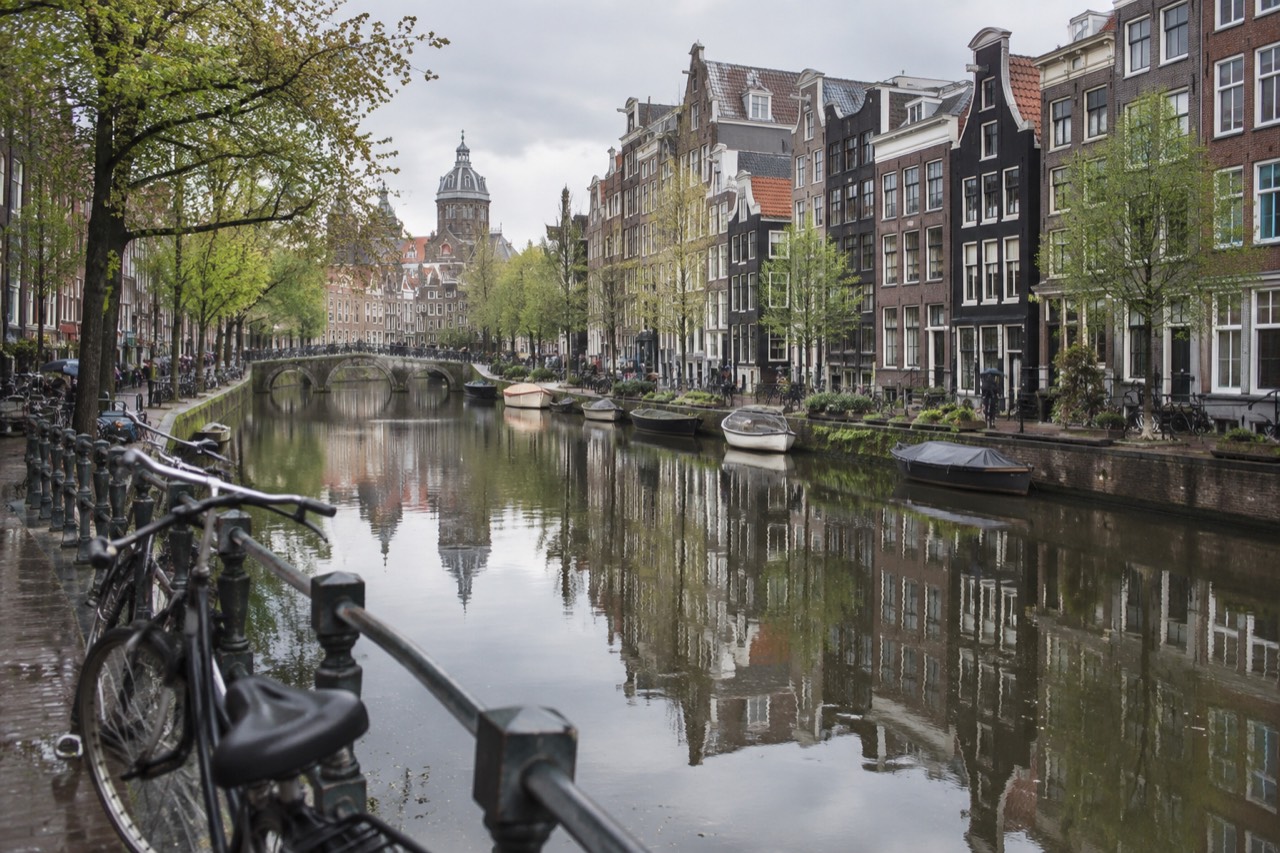 Amsterdam canal houses reflected in still water on a bright spring morning