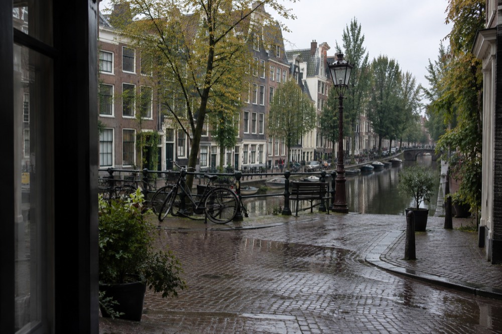 A quiet Jordaan street corner with canal houses reflected in still water