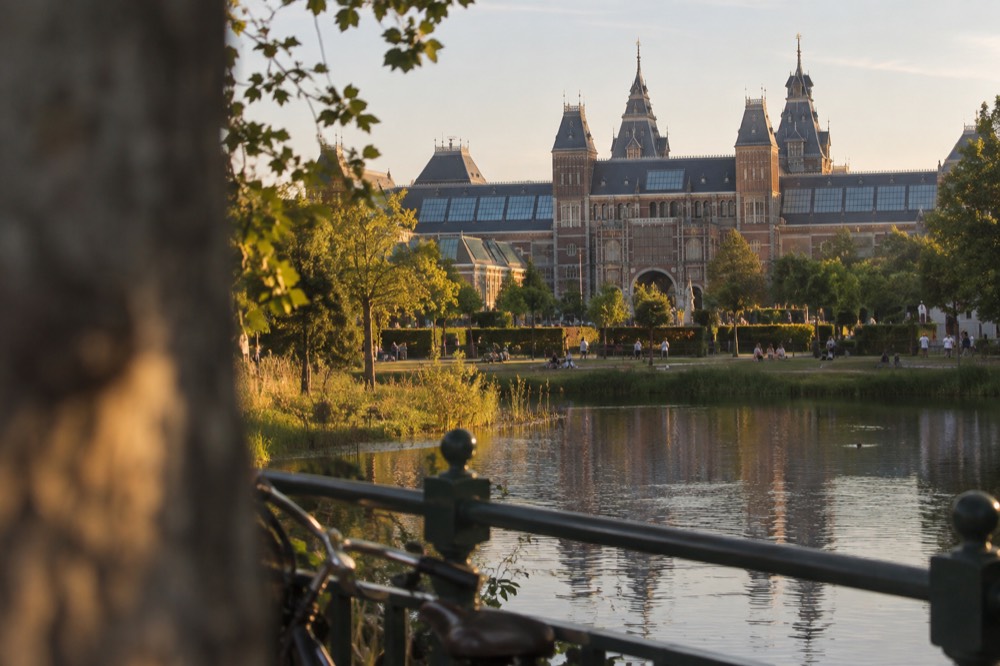 The Rijksmuseum facade and its garden seen across the water on a summer evening