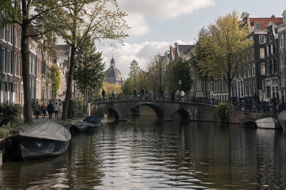 A stone bridge over an Amsterdam canal with narrow gabled houses on both sides