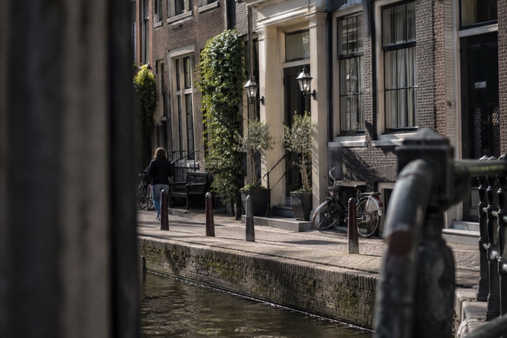 A narrow Amsterdam street with a small independent hotel entrance and bicycles outside