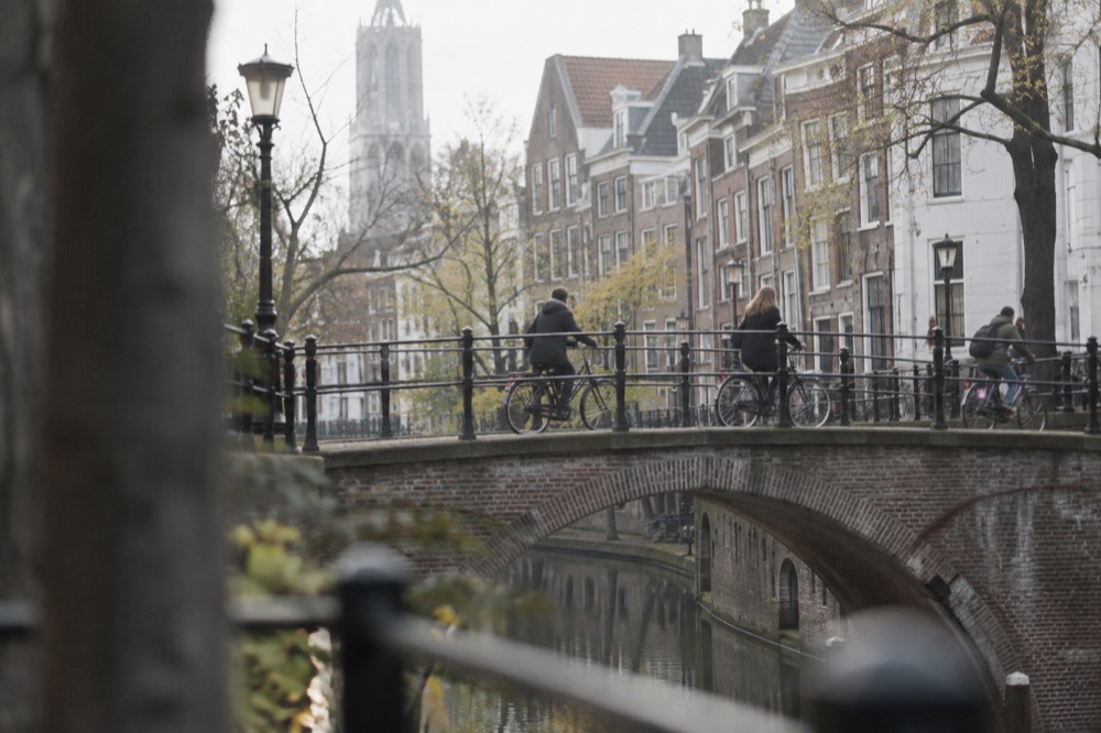 Cyclists crossing a bridge over a canal in central Utrecht with old brick buildings