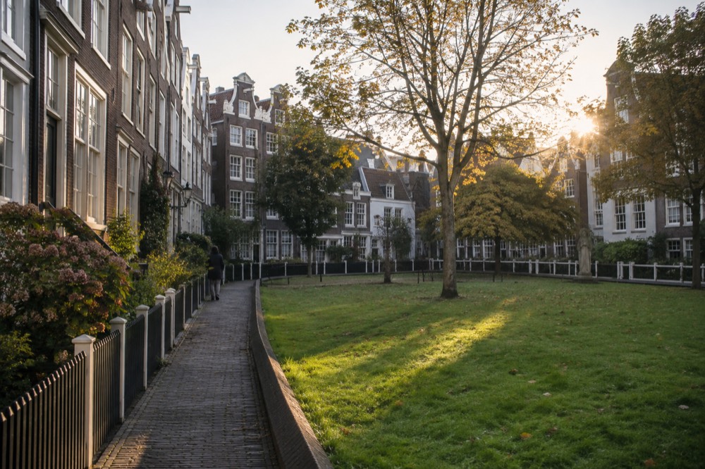 Narrow tall brick houses with white window frames enclosing a small green lawn in a quiet courtyard