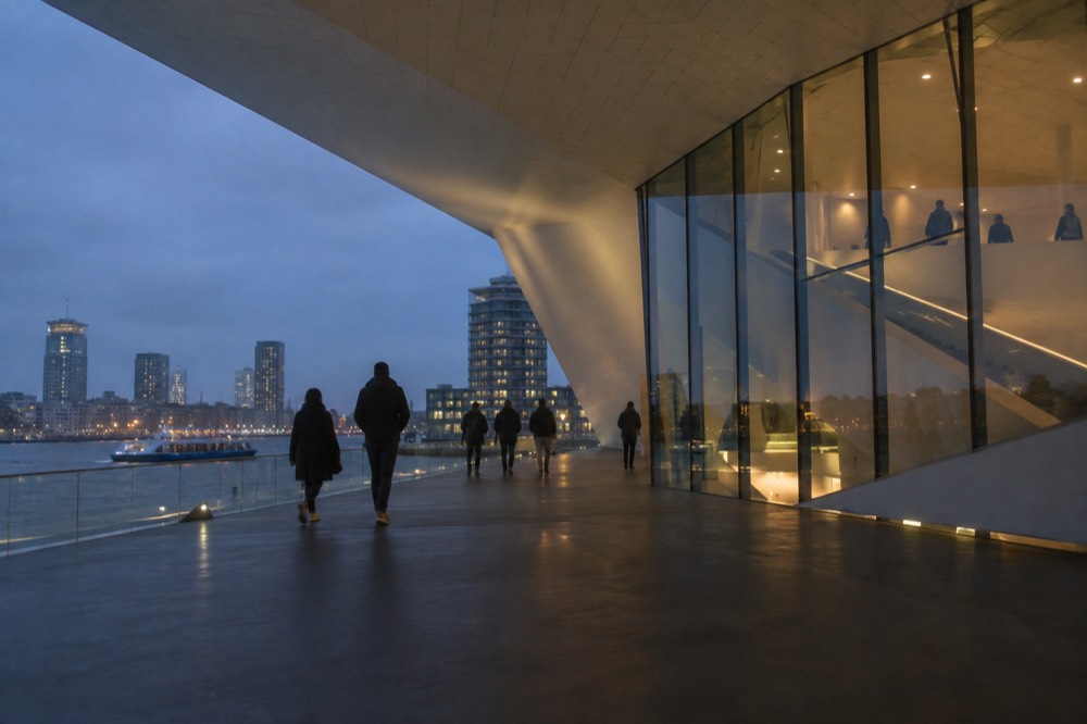 Visitors walking through a dim exhibition hall with projected moving images at the Eye Filmmuseum
