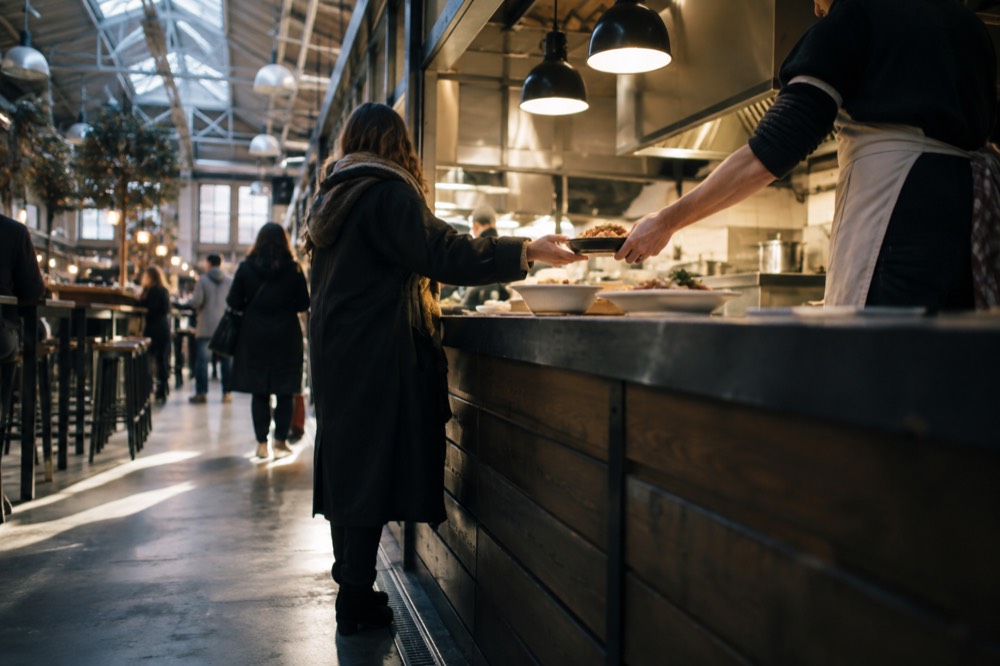 Food hall counter with dishes being handed over a service counter in the evening