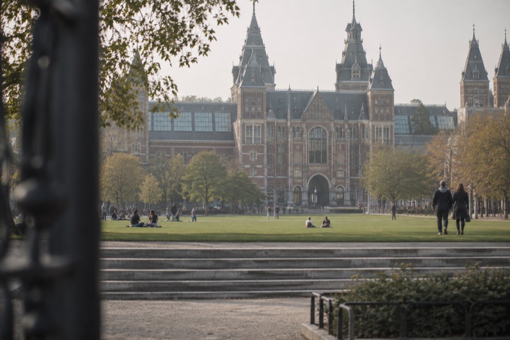 A grand red-brick museum building seen across a green lawn with wide stone steps