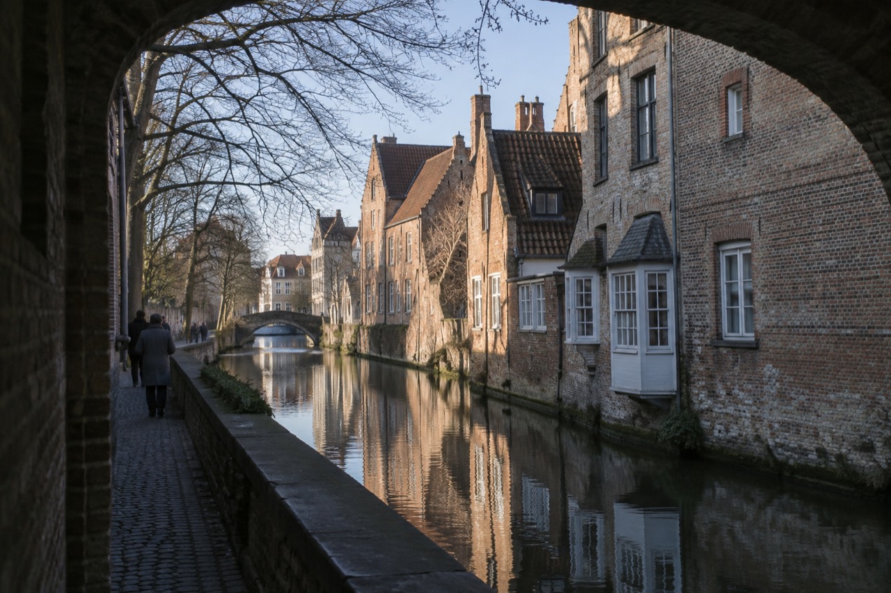 Medieval brick buildings and a quiet canal reflecting the facades of Bruges