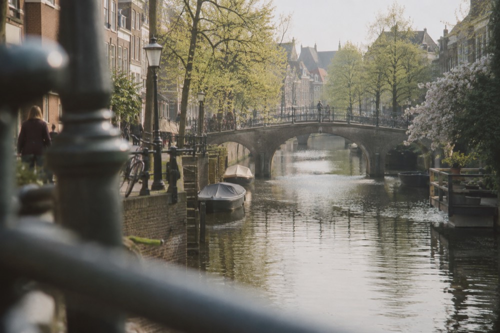 A canal in Leiden lined with small bridges and brick buildings in spring light