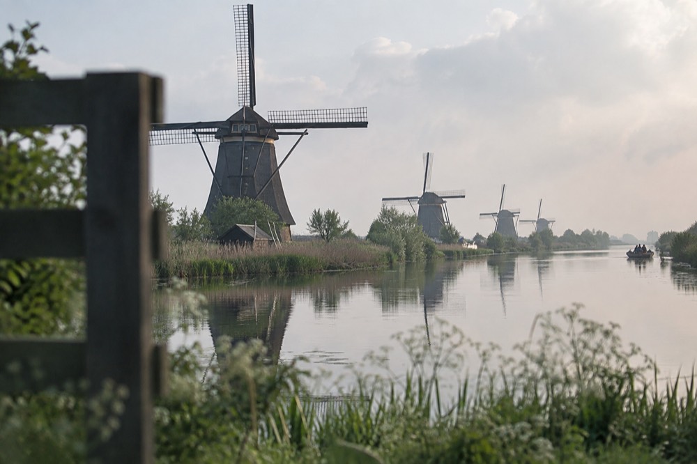 A row of traditional windmills reflected in a calm canal