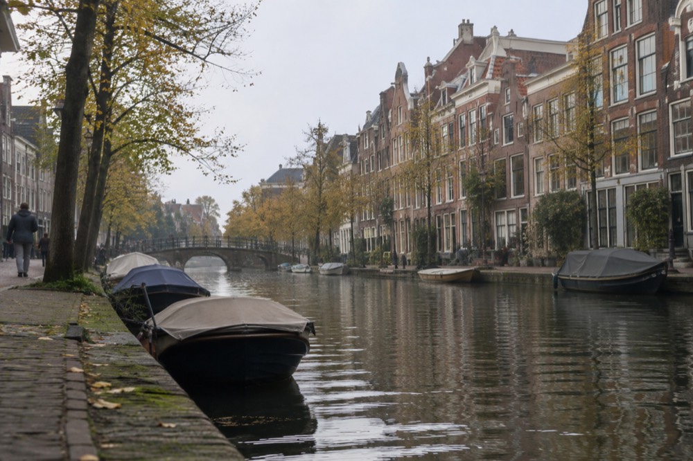A quiet canal in Leiden lined with brick merchant houses and small boats
