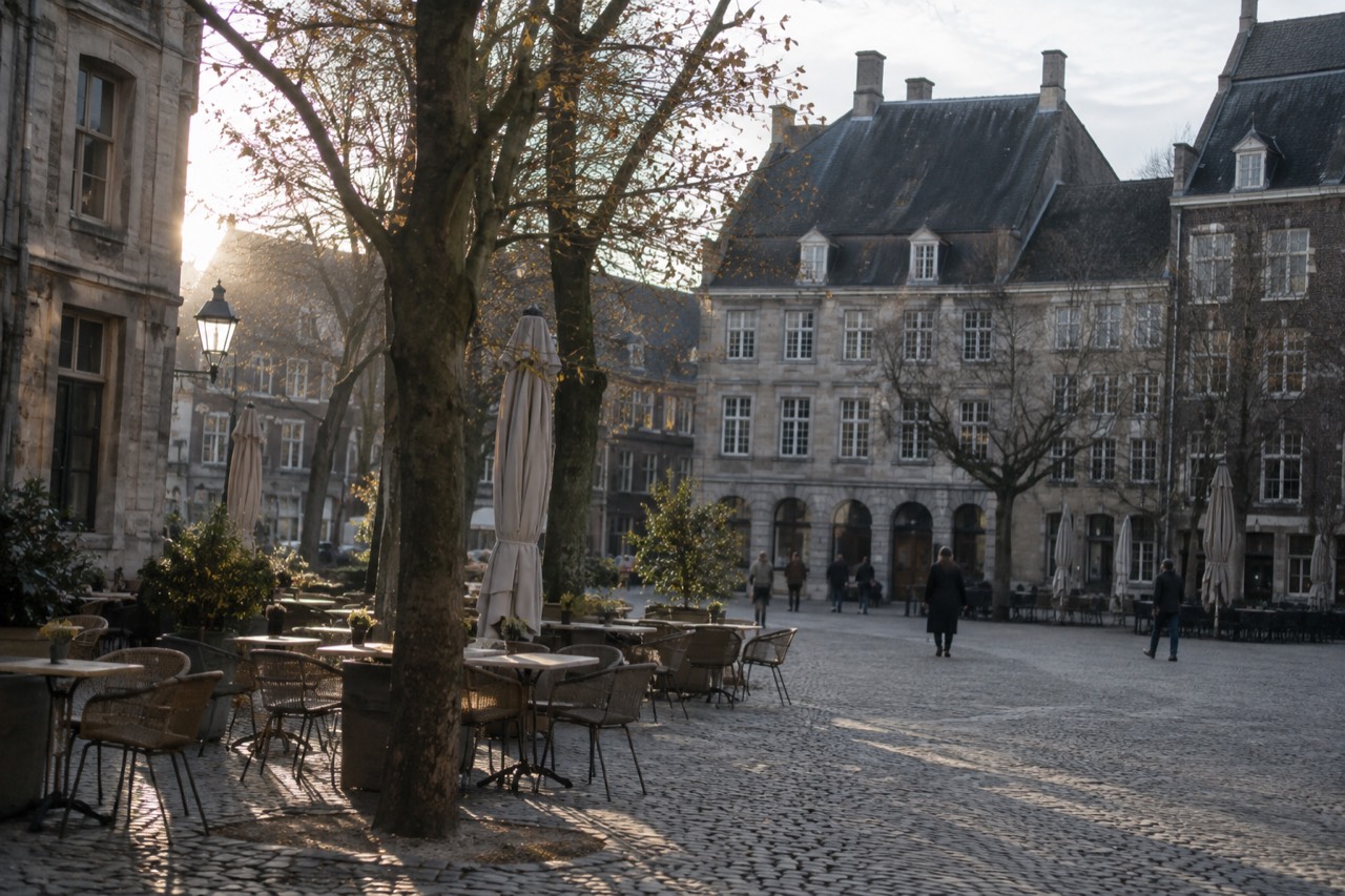 A quiet square in Maastricht with old stone buildings and cafe tables under trees