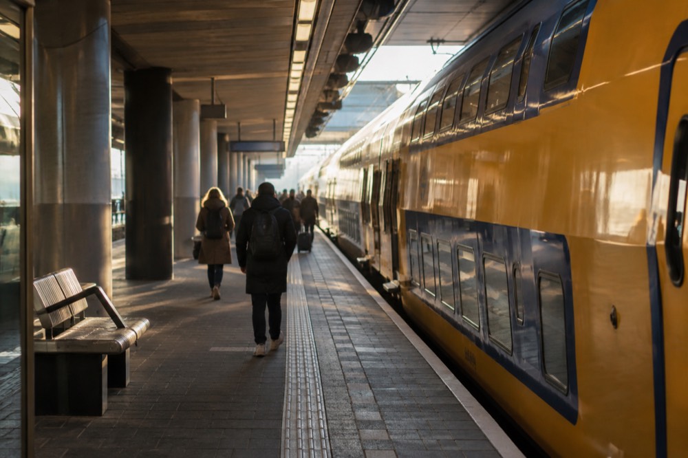 An NS train platform beneath Schiphol Airport with a double-decker train at the platform edge