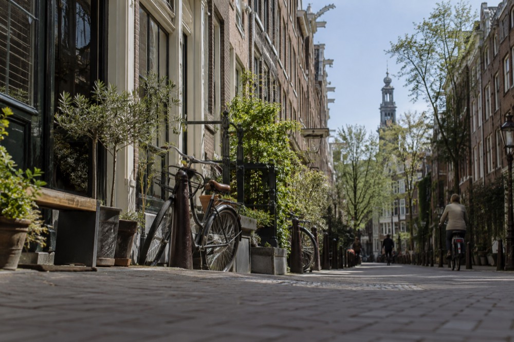 A narrow Amsterdam street in the Jordaan with small shops and bicycles parked against railings