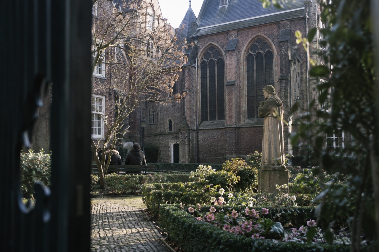A quiet hidden courtyard with a historic chapel and blooming flowers, away from the crowds