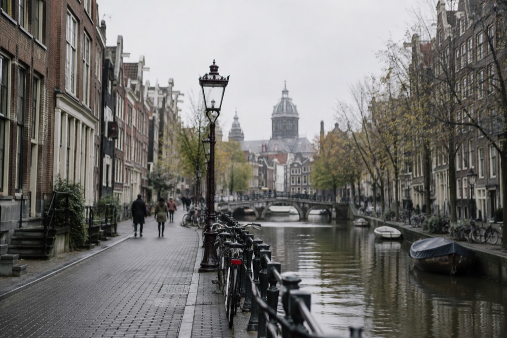 Narrow Amsterdam street with tall gabled houses and bicycles parked against a railing