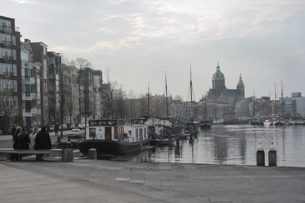 Modern apartment buildings and moored boats along a wide harbour with open sky