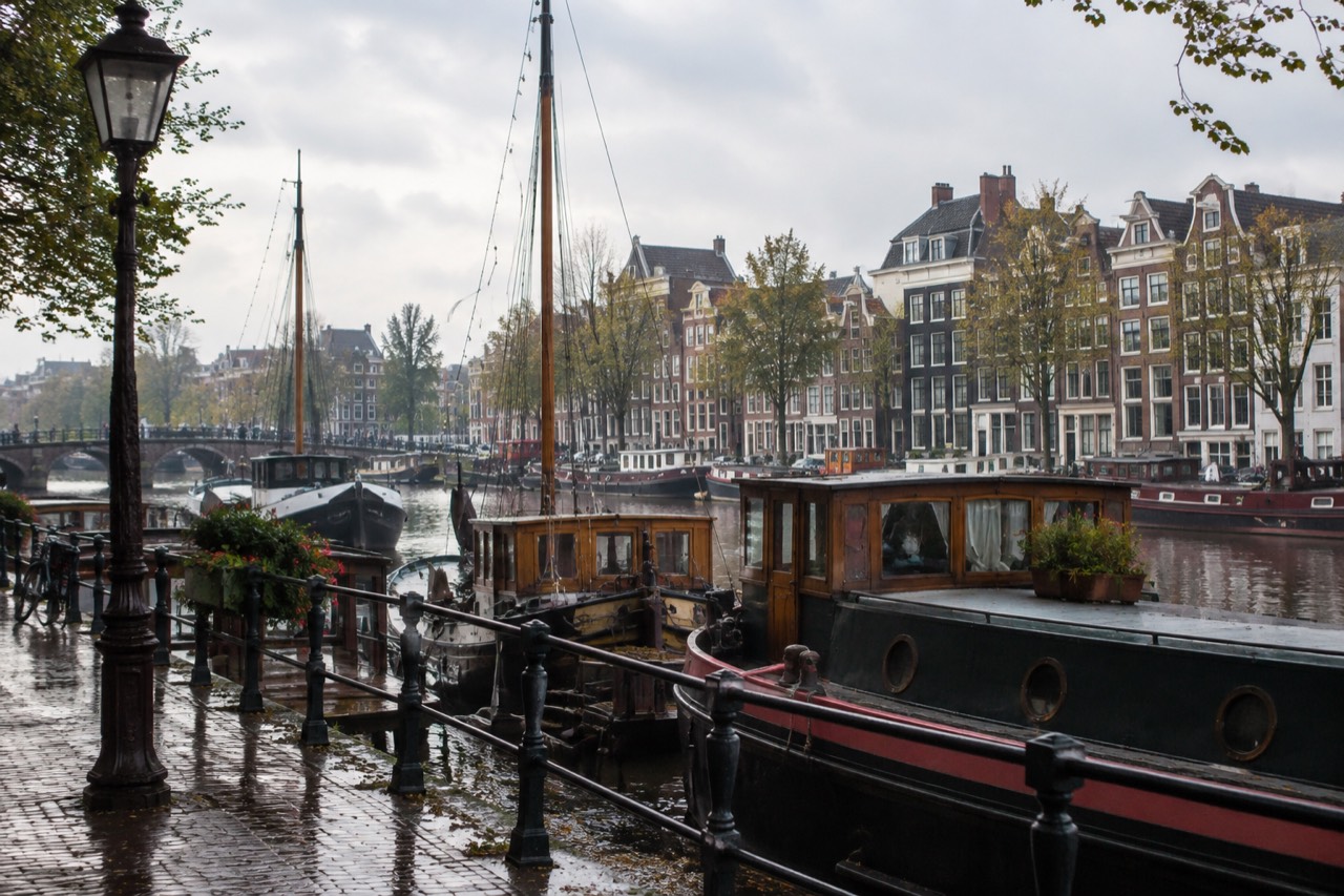 Decorated boats moored along an Amsterdam canal with gabled houses behind them