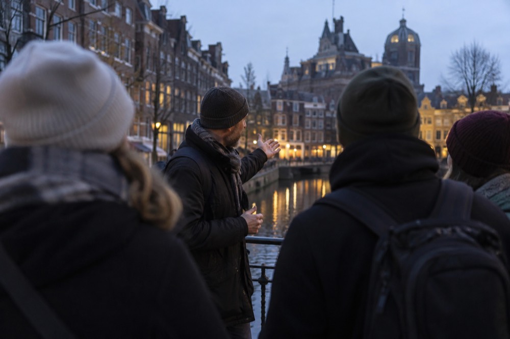 A guide speaking to a small group beside a canal bridge in central Amsterdam