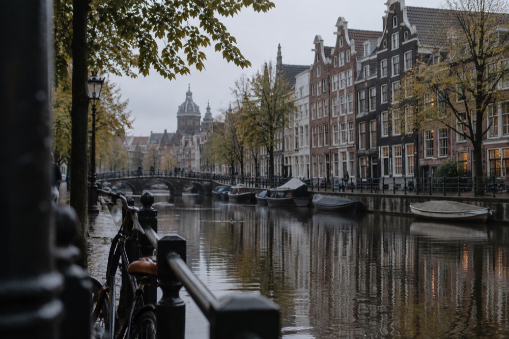 A quiet Amsterdam canal in the morning with narrow gabled houses reflected in the water