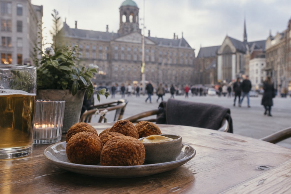 A plate of bitterballen with a small dish of mustard on a wooden café table