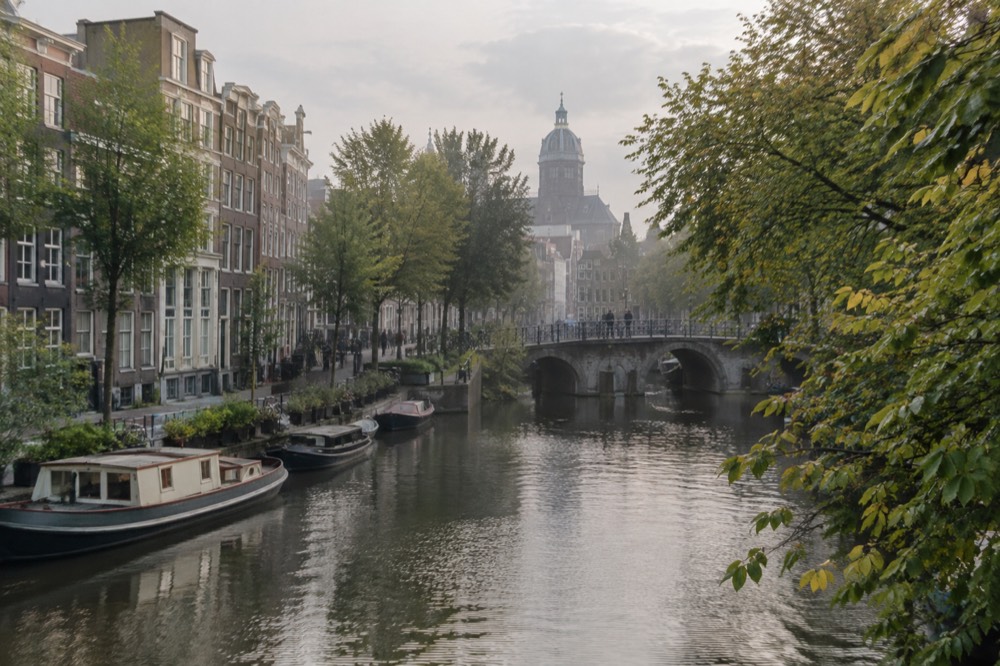 A quiet corner of Dam Square with trees overhanging the water