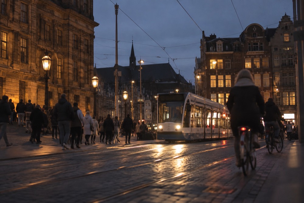 A busy Amsterdam street with trams, cyclists and tall narrow buildings