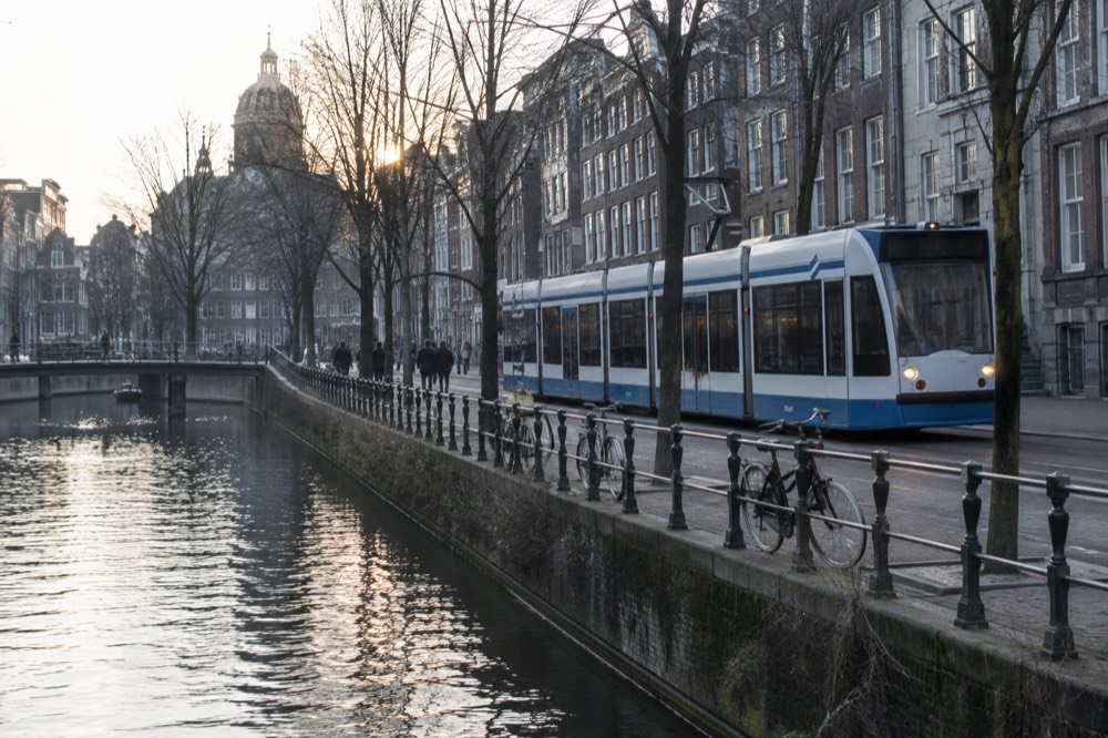 A tram moving along tracks beside a canal in central Amsterdam