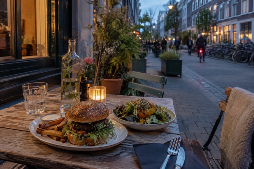 Vegan burger and salad served on a terrace table on a De Pijp side street