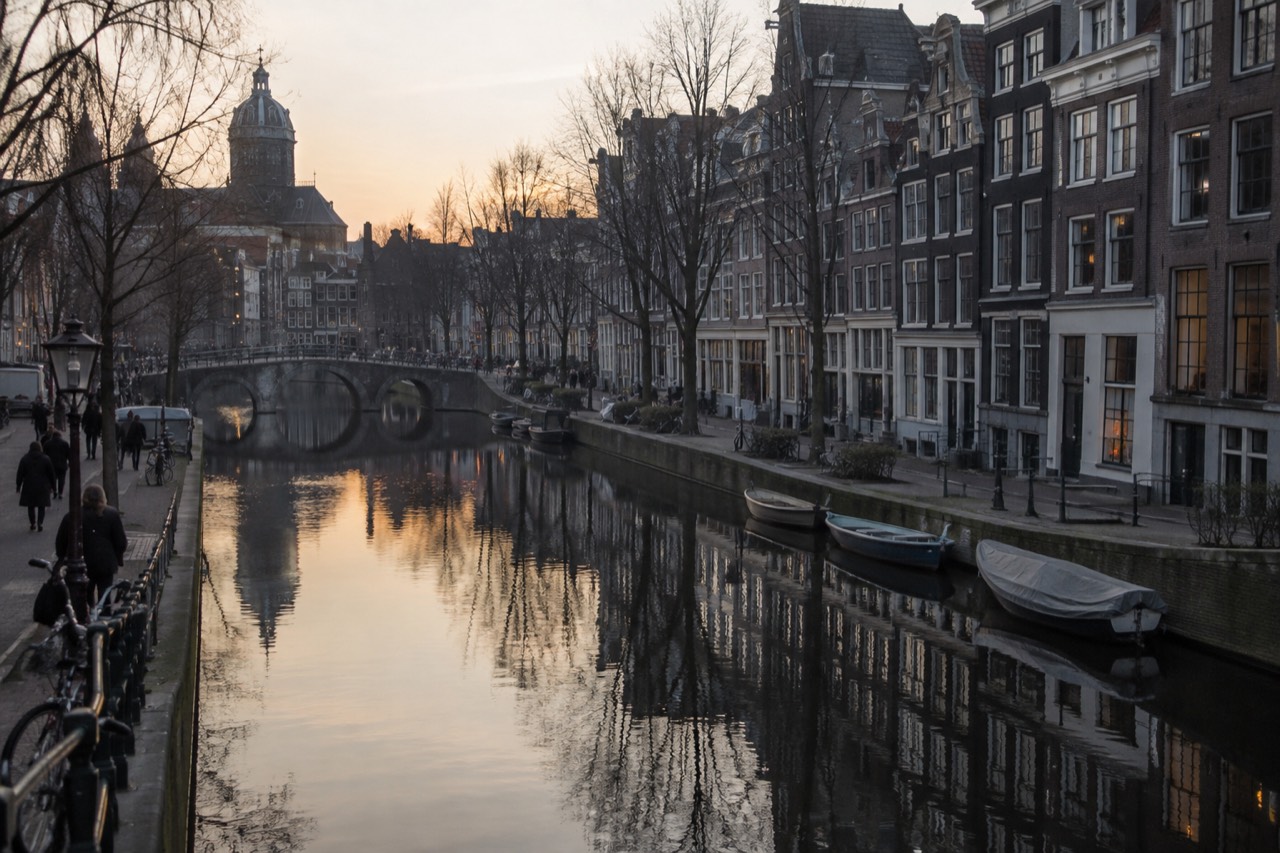 Canal houses reflected in still water along a quiet Amsterdam gracht at dusk