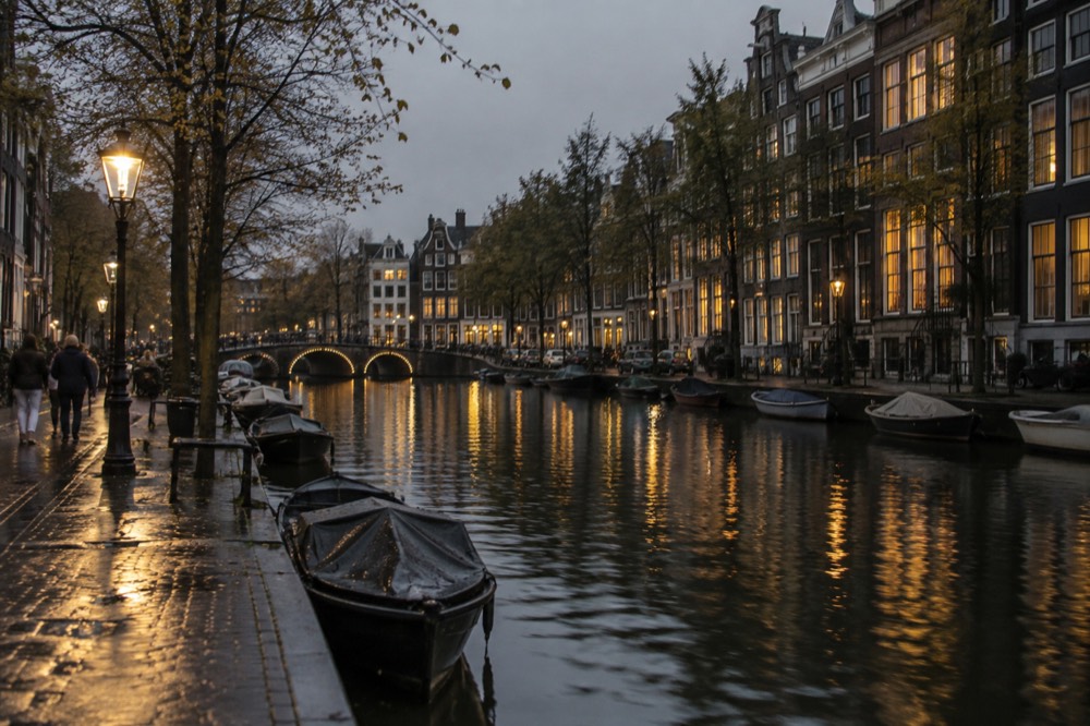 Illuminated canal houses reflected in dark water along an Amsterdam gracht at night