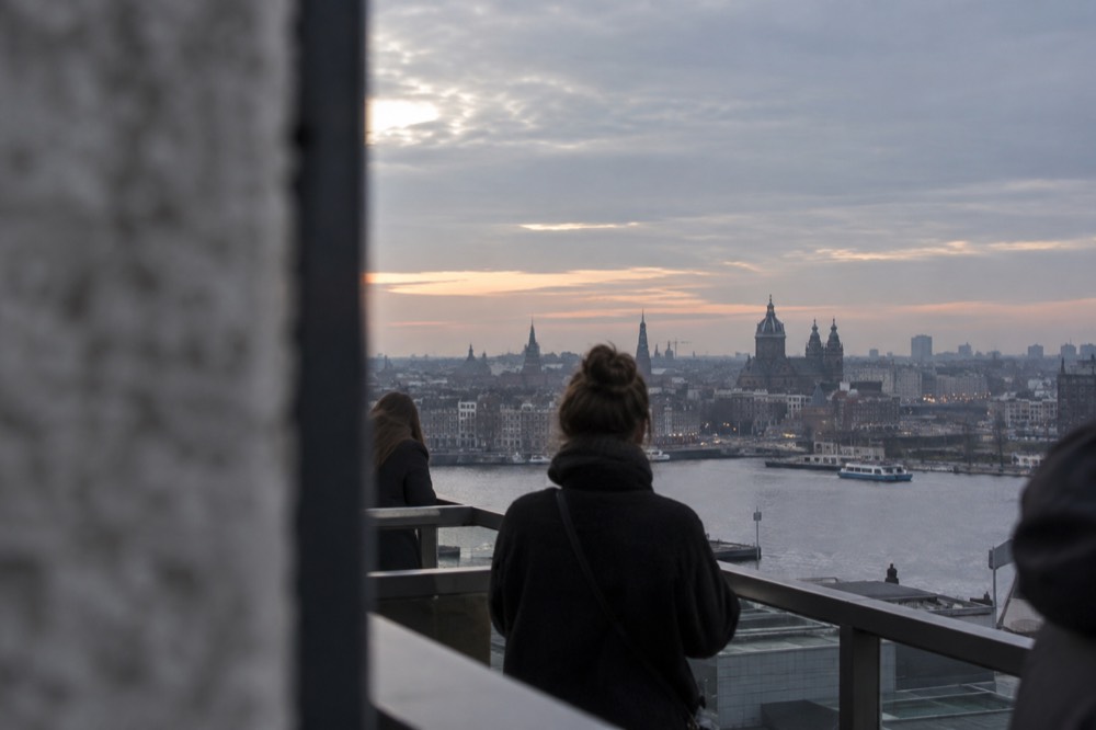 An observation deck terrace overlooking the Amsterdam skyline across the river IJ at dusk